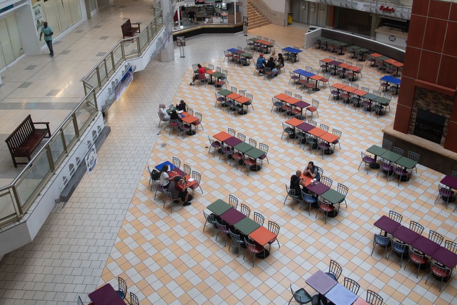 Aerial view of a sparse food court in a shopping mall with few people present, showcasing empty tables.