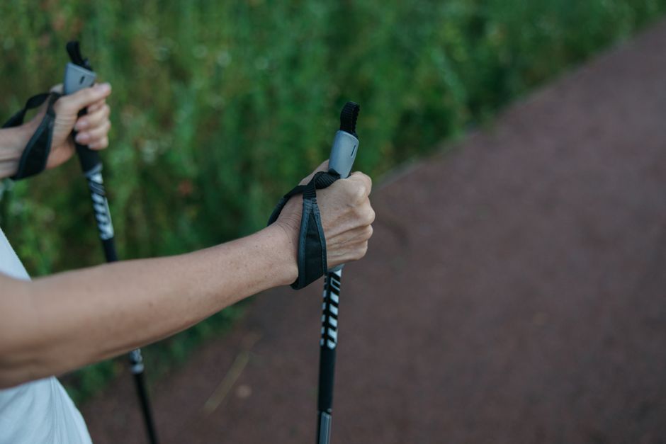 Close-up image of hands gripping walking poles on a trail, showcasing outdoor fitness activity.