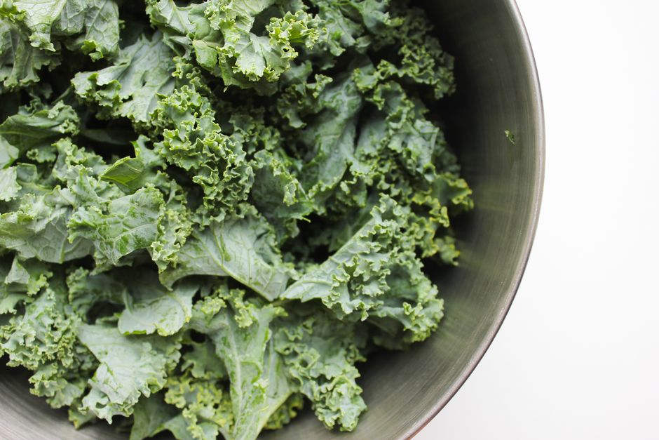 Close-up of fresh organic kale leaves in a stainless steel bowl, emphasizing health and nutrition.
