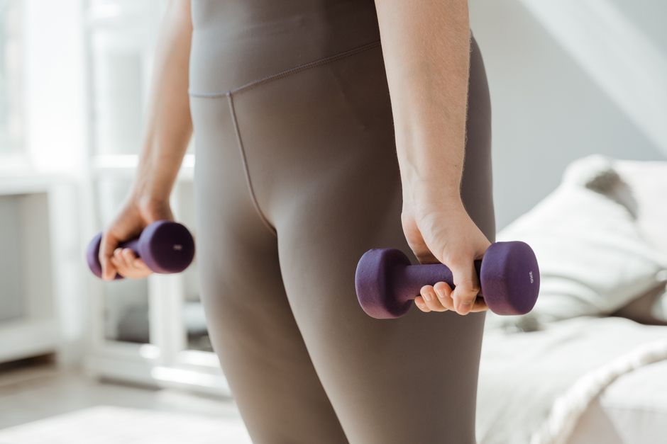 Close-up shot of a person holding purple dumbbells, symbolizing fitness and healthy living.