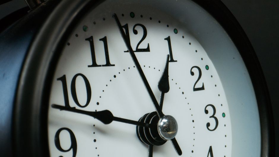 Detailed macro shot of an analog clock showing time at 12:05.
