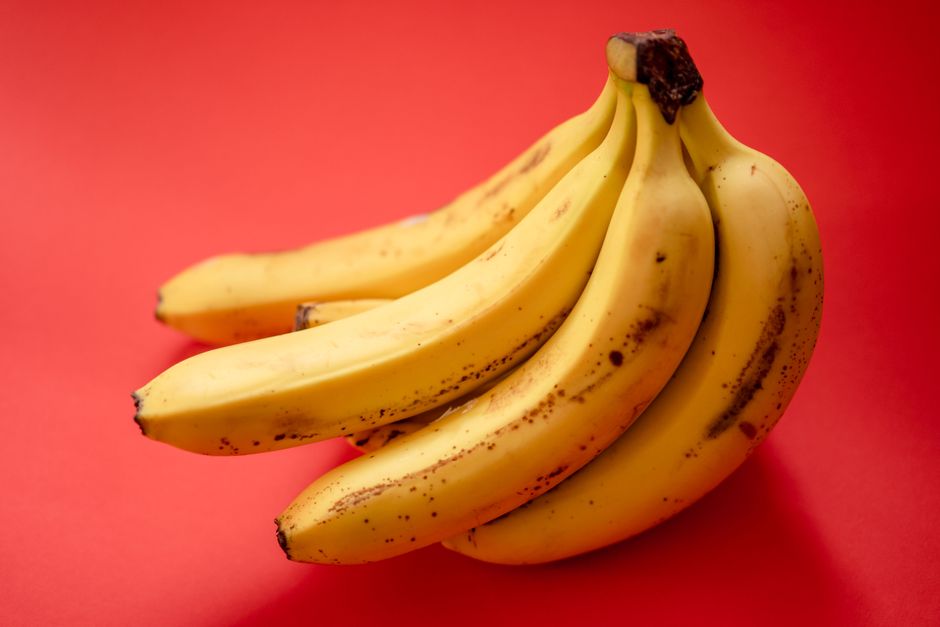 Fresh ripe bananas displayed against a vibrant red background.