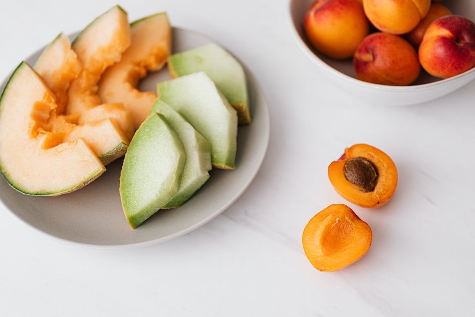 From above of fresh fruits in bowl and plate placed on marble table