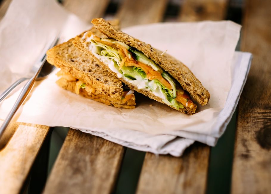 Gourmet smoked salmon sandwich with lettuce on a rustic wooden table.