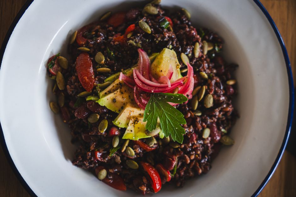 Healthy vegan black rice salad topped with avocado, pickled onions, and pumpkin seeds.