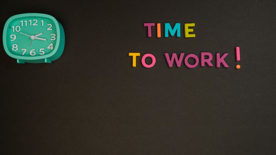 Minimalist image with a colorful clock and letters spelling 'Time to Work' on a black background.