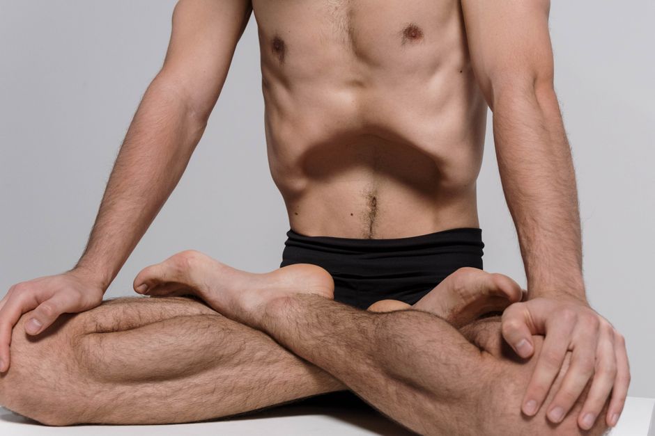 Shirtless man practicing yoga, seated with legs crossed in a meditative pose.