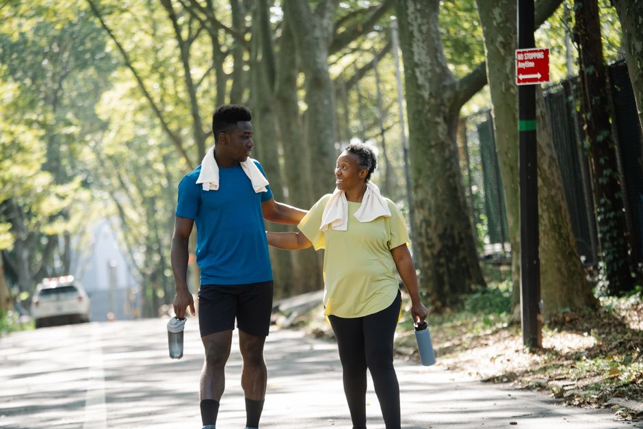 Two people jogging in a sunlit park, promoting fitness and well-being.