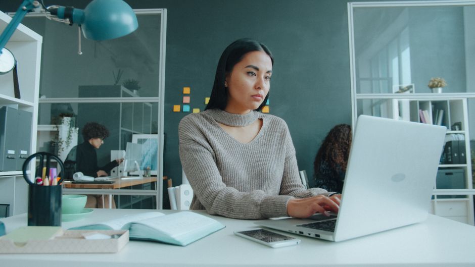 Young woman concentrating on her laptop in a stylish office environment.